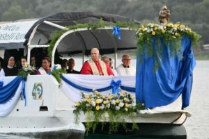 Entre a margem e o horizonte, a barca de Pedro atravessa o Lago Albano com Maria